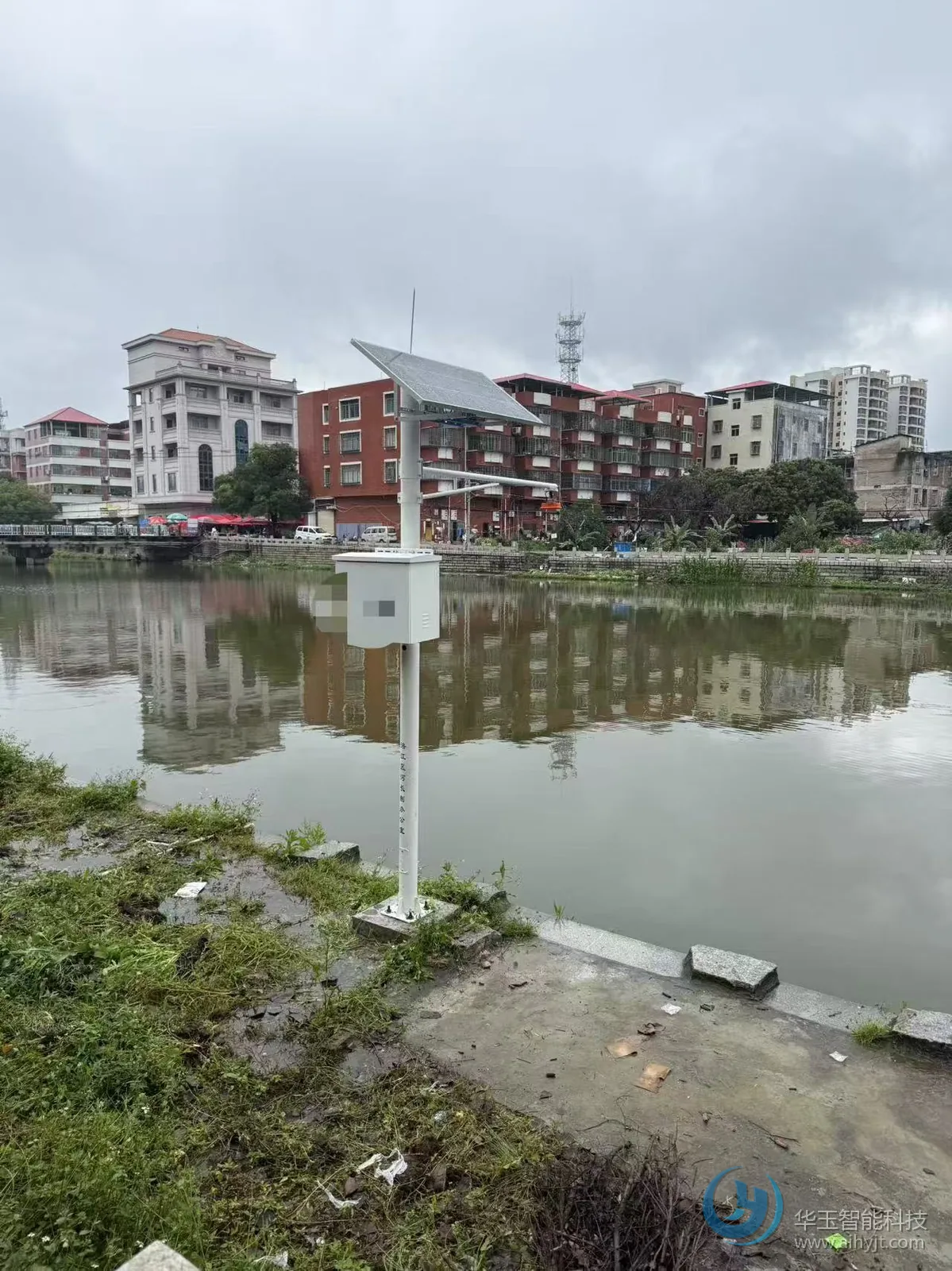 河道水位监测站现场：立杆安装的太阳能板、遥测终端机箱与水位计